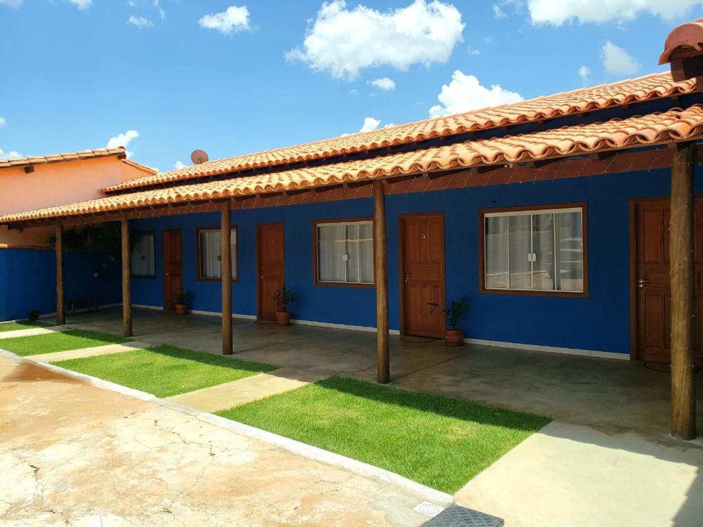 een blauw huis met een rood dak bij Pousada Recanto Rainha do Lago in Capitólio