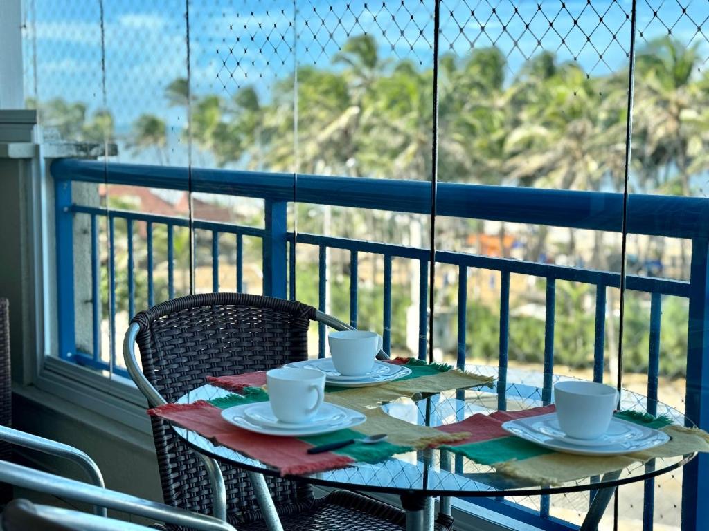 a table with cups and saucers on a balcony at AllMar Flats - Apartamentos frente mar - Beach Village in Fortaleza