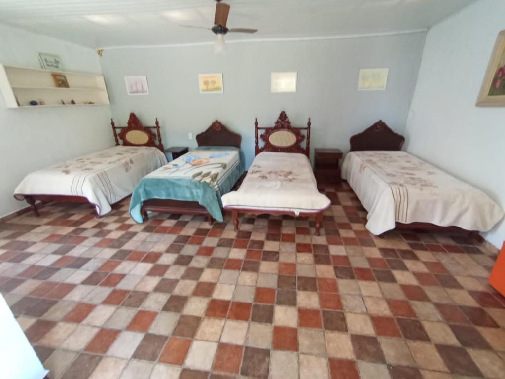 three beds in a room with a checkered floor at Suites Delicia in Passa Quatro