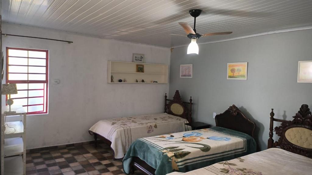 1 Schlafzimmer mit 2 Betten und einem Deckenventilator in der Unterkunft Suites Delicia in Passa Quatro