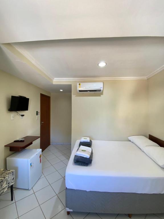 阿拉克魯斯的住宿－Buriti Hotel - Barra do Riacho, Aracruz ES，一间卧室配有一张床、一张书桌和一台电视。