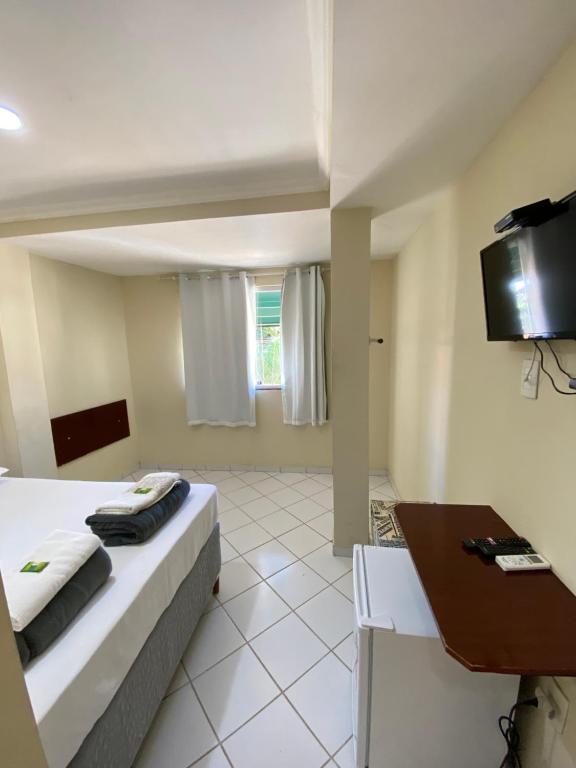um quarto de hotel com uma cama e uma televisão em Buriti Hotel - Barra do Riacho, Aracruz ES em Aracruz