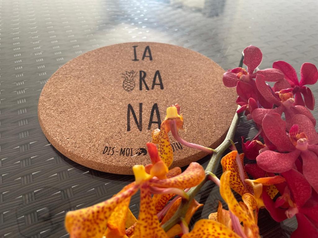 a cork board with the words la na nana next to flowers at Appartement avec vue sur le port de Papeete in Faaa