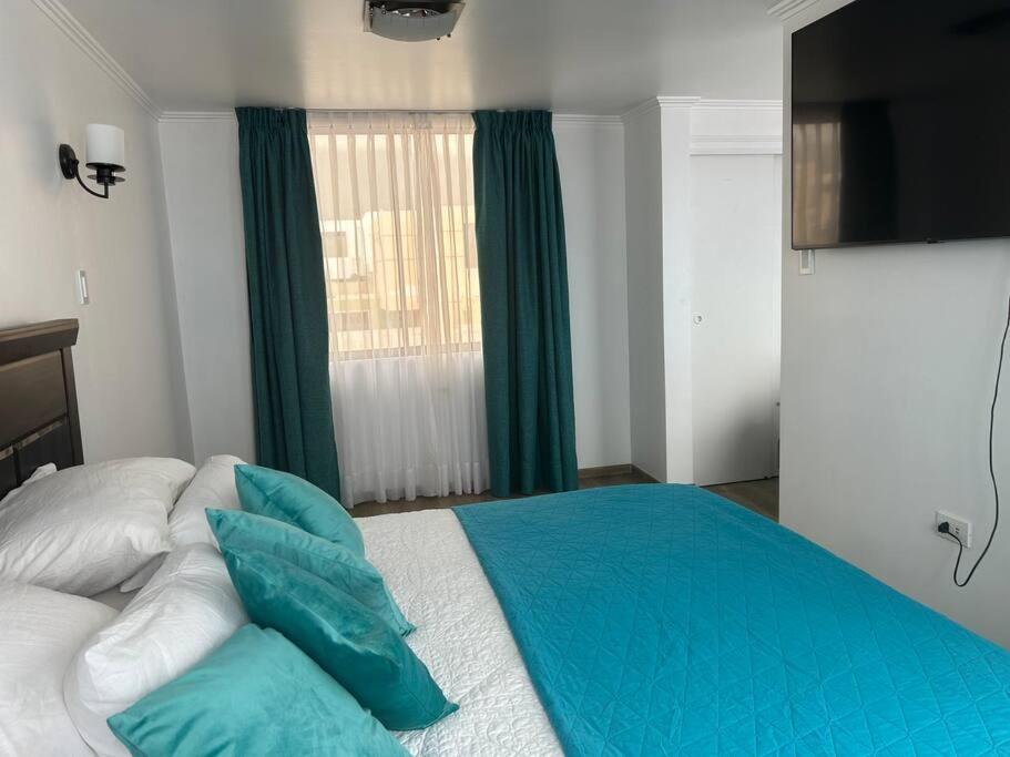 a bedroom with a bed with blue pillows and a window at Espectacular casa para la Exponor in Antofagasta