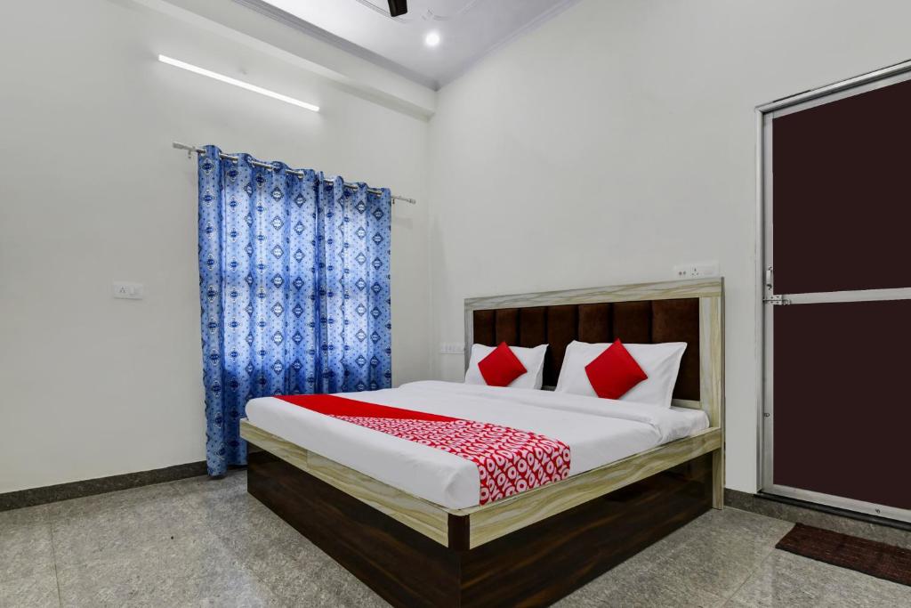 1 dormitorio con 1 cama con cortinas rojas y azules en OYO Hotel Ishwar en Jaipur