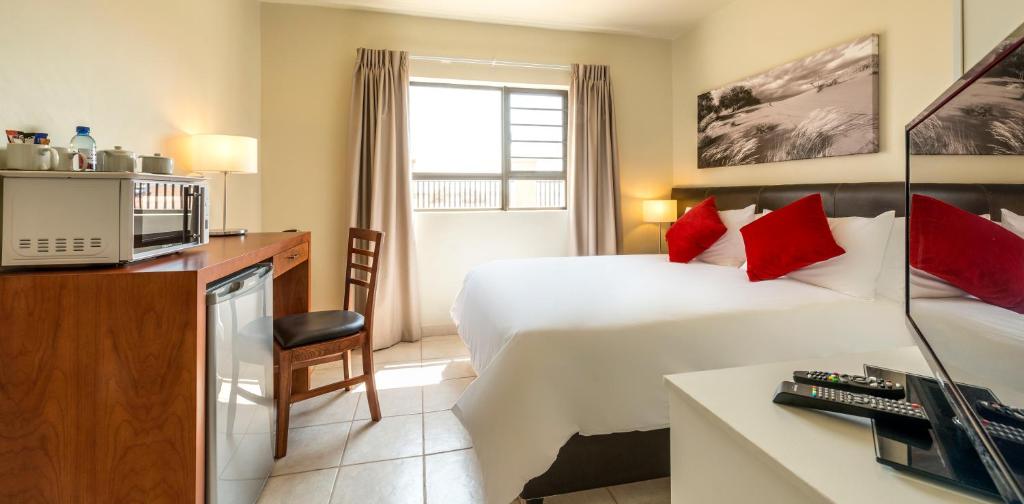 una habitación de hotel con una cama grande con almohadas rojas en Kathu Inn, en Kathu
