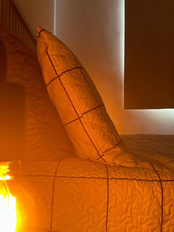 un letto con cuscino arancione accanto a una lampada di Apê da Sil a San Paolo