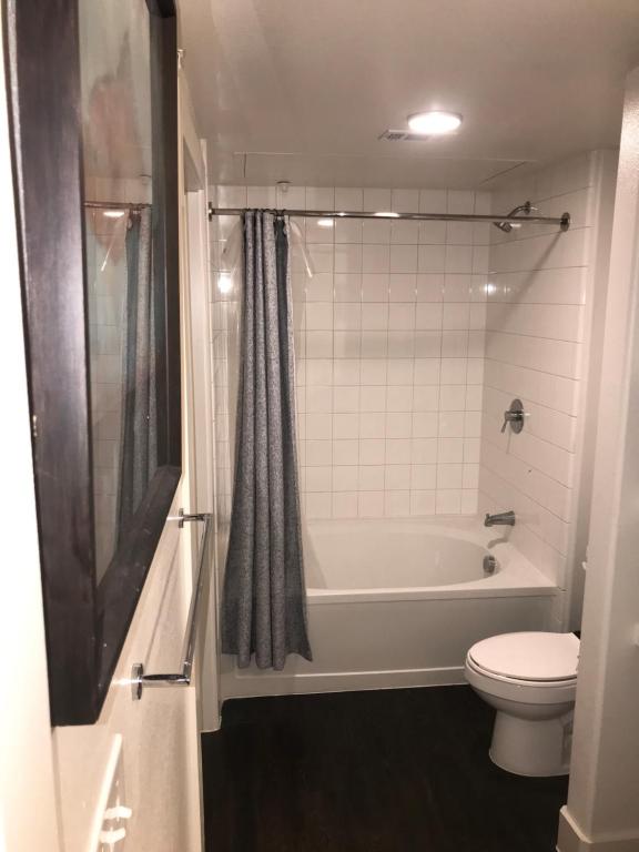 a bathroom with a white tub and a toilet at Comfy and Cozy Legacy West Apartment steps from everything in Plano