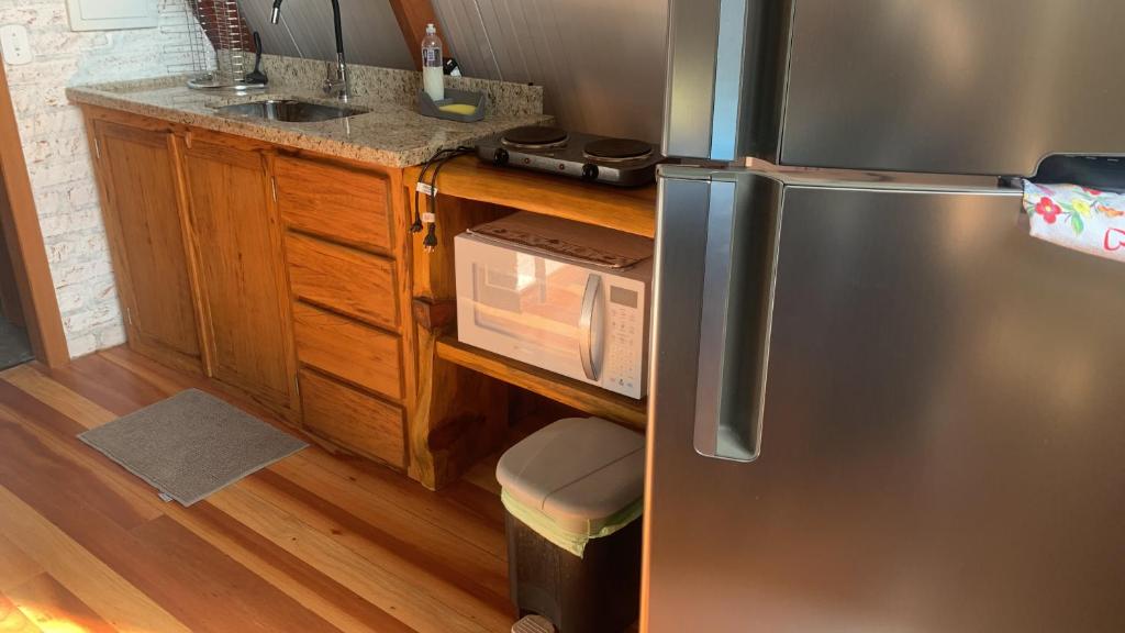 La cuisine est équipée d'un réfrigérateur en acier inoxydable et d'un évier. dans l'établissement Chalés Roma, à Santo Antônio do Pinhal