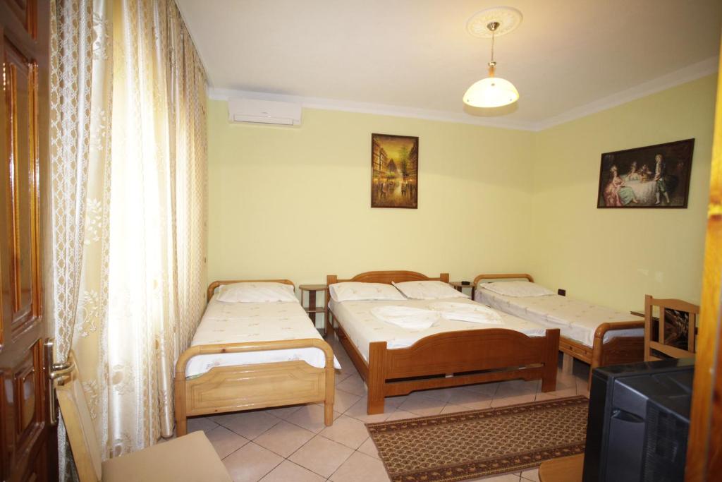 Zimmer mit 4 Betten und einem TV. in der Unterkunft Alen Bar Hotel in Tirana