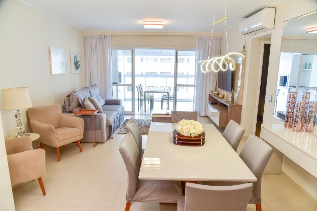 a dining room and living room with a table and chairs at Apartamento 3 quartos em Pitangueiras in Guarujá
