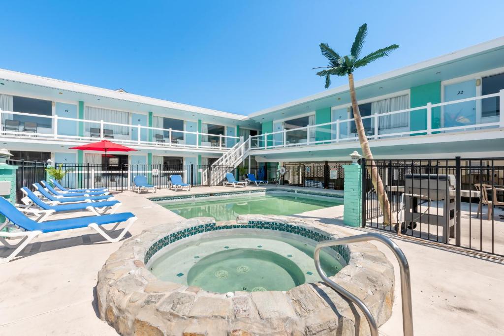 une piscine avec un palmier et un bâtiment dans l'établissement Mango Motel, à Wildwood