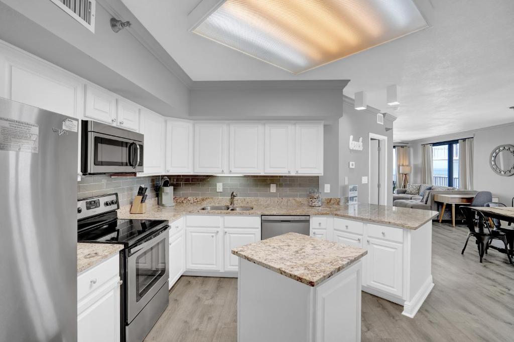 a kitchen with white cabinets and a dining room at Windward Pointe 706 in Orange Beach