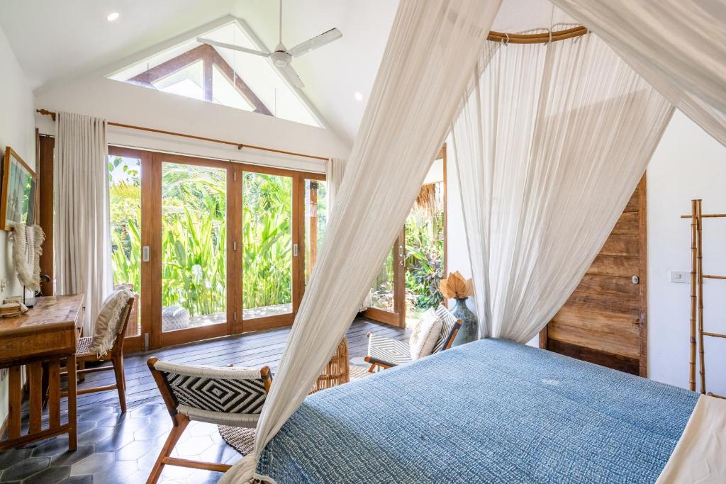 a bedroom with a bed and a desk and windows at Ohana Boutique Villa by Hombali in Canggu