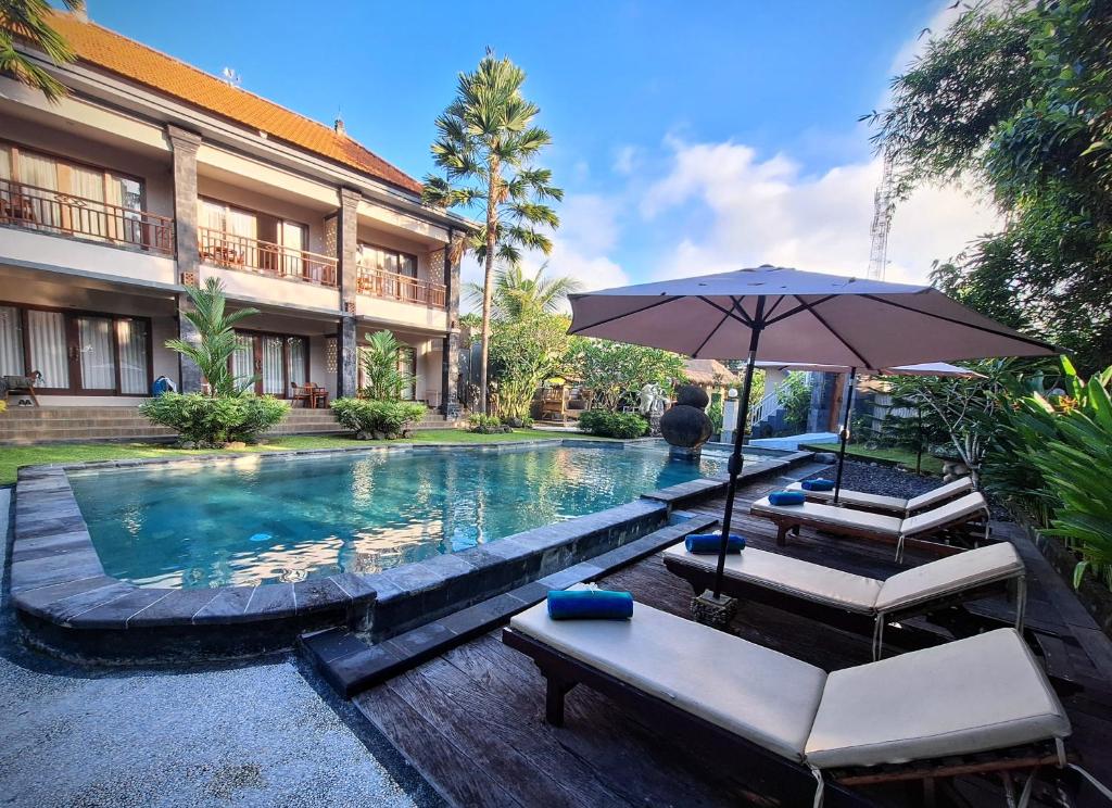 - une piscine avec 2 chaises et un parasol dans l'établissement Bambu Lokha Guest house, Gianyar Bali, à Ubud