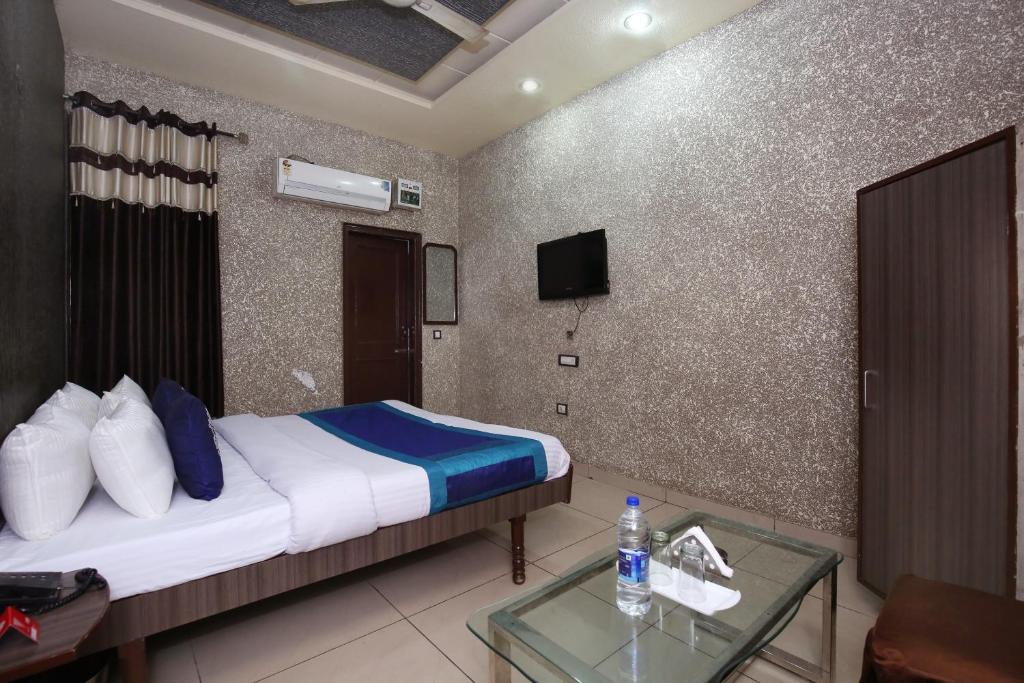 a bedroom with a bed and a table and a tv at OYO 9808 Hotel Prem Sagar in Ludhiana