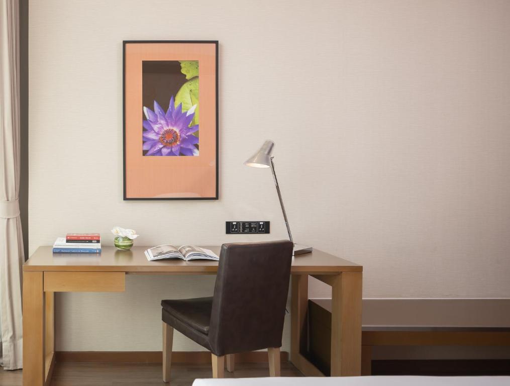A compact writing desk with lamp and chair is set against a quiet neutral wall.