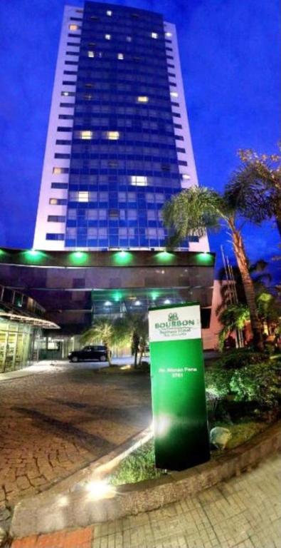 a tall building with a green sign in front of it at Flat BH Savassi in Belo Horizonte