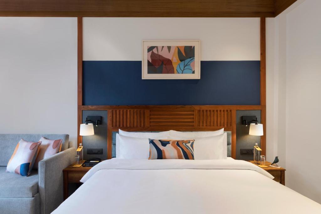 拉姆納格爾的住宿－voco Jim Corbett, an IHG Hotel，卧室配有一张白色的大床和一张沙发。