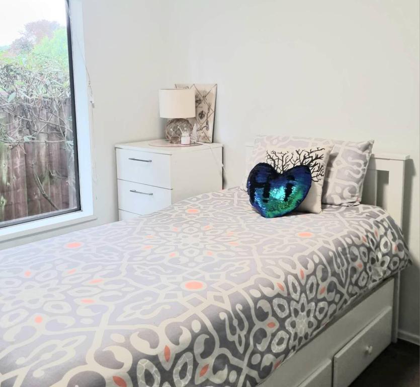 ein Schlafzimmer mit einem Bett mit einem Herzkissen drauf in der Unterkunft Cozy Room Near Christchurch Airport in Christchurch