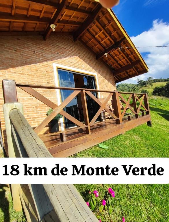 um portão de madeira para uma casa com varanda em Chalé Sonho Diniz 2 em Monte Verde