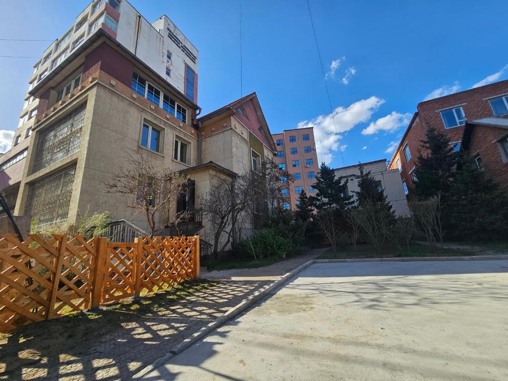 a building with a wooden fence next to a street at Moncozy guesthouse in Ulaanbaatar