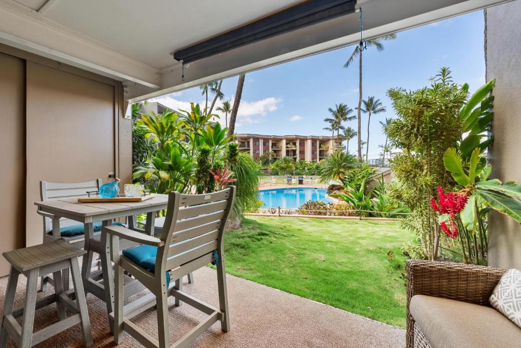 a patio with a table and chairs and a view of a pool at Hale Ono Loa 104 in Kahana