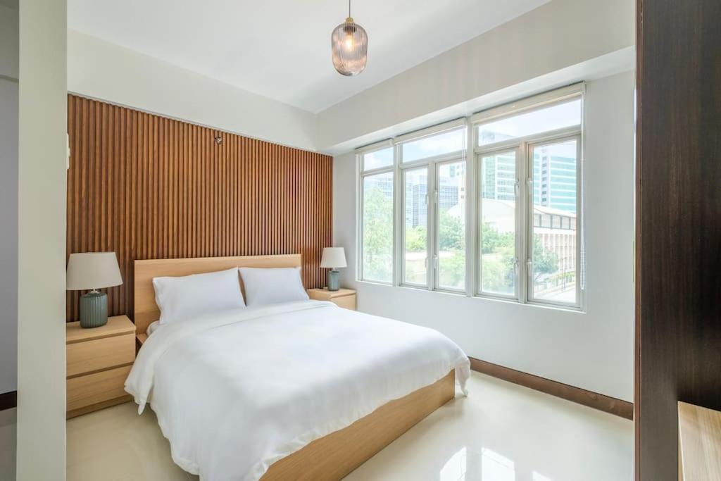 um quarto com uma grande cama branca e uma janela em Modern Stylish Condo in Stamford McKinley Wi-Fi em Manilla