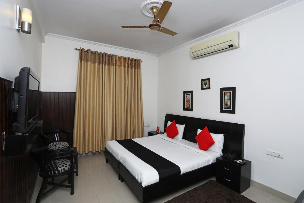 a bedroom with a bed with red pillows at Capital O 7302 The Huespedes in Gurgaon