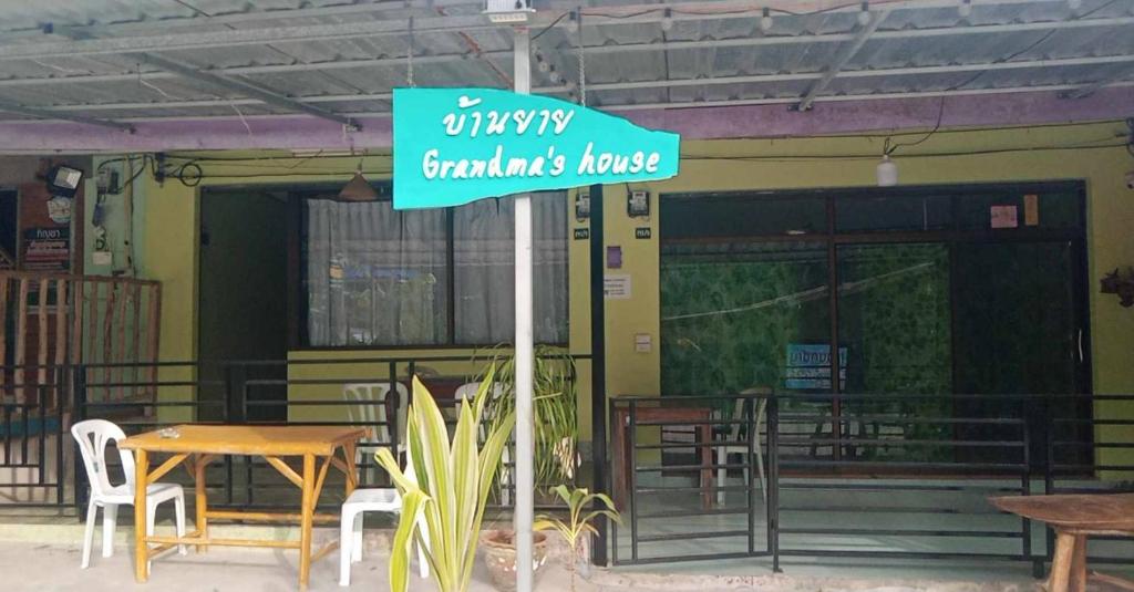 a sign in front of a restaurant with a table and chairs at Grandma's House in Khao Sok National Park