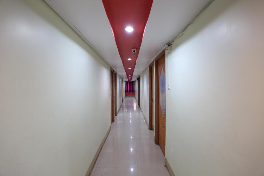 un largo pasillo con paredes blancas y techo rojo en New Mega Palace en Bankipur