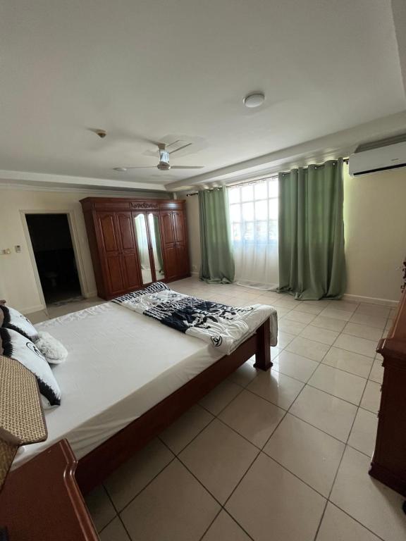 een slaapkamer met een groot bed en groene gordijnen bij FINE HOMES MIKOCHENI in Dar es Salaam