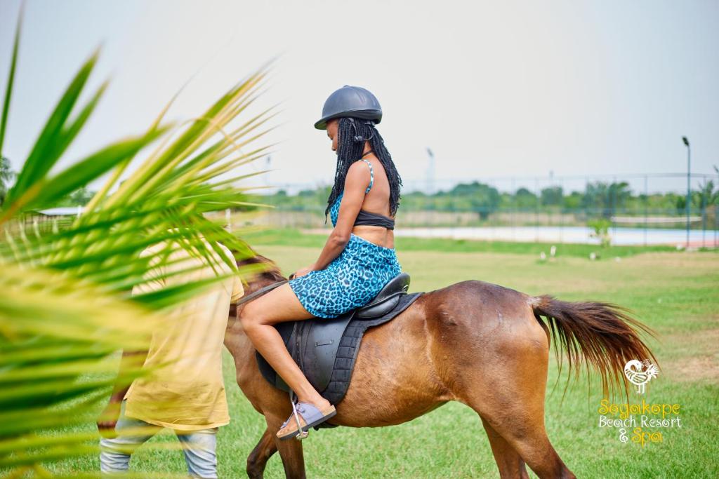 Eine Frau in einem Kleid, die auf einem Pferd sitzt in der Unterkunft Sogakope Beach Resort & Spa in Sogakofe