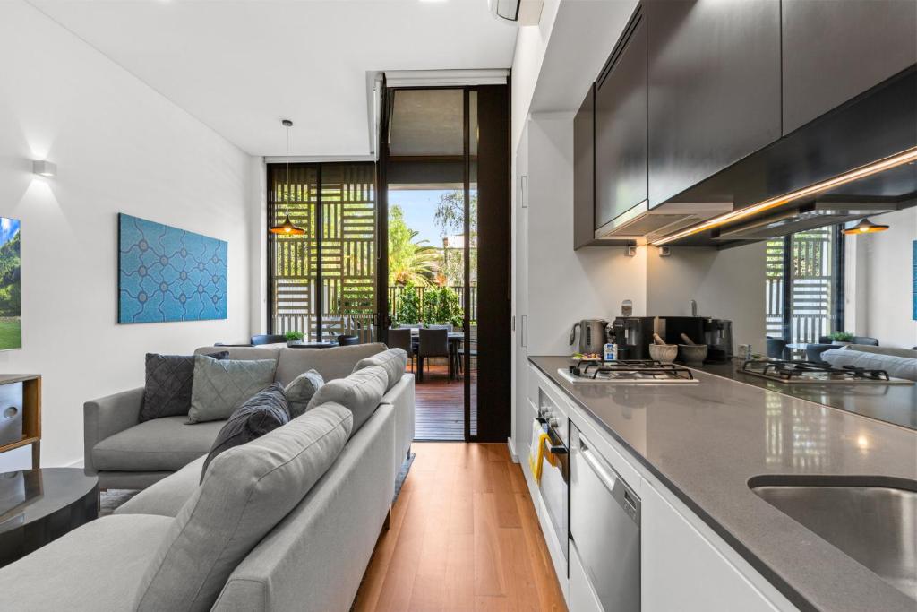 a living room with a couch and a kitchen at 1-Bed Unit with Alfresco Dining and BBQ in Sydney