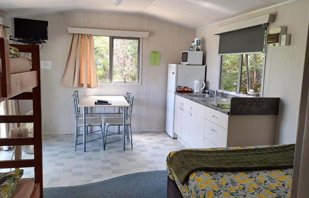 eine kleine Küche mit einem Tisch und einem Kühlschrank in der Unterkunft Whatuwhiwhi TOP 10 Holiday Park in Tokerau Beach