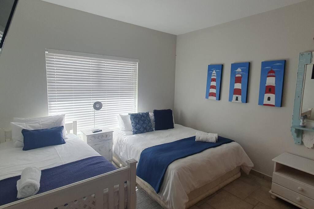 a bedroom with two beds and a window with two lamps at Sunset View 10 @ Langstrand in Langstrand