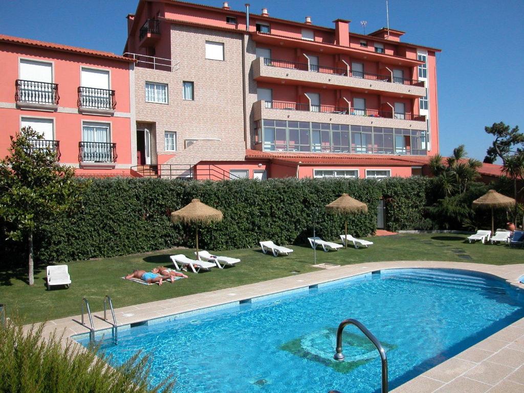 a swimming pool in front of a large building at Hotel VIDA Playa Paxariñas in Portonovo