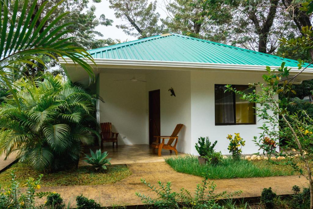 una pequeña casa blanca con techo verde en Buddha Hotel y Restaurante 100mts de playa Sanjuanillo, en San Juanillo