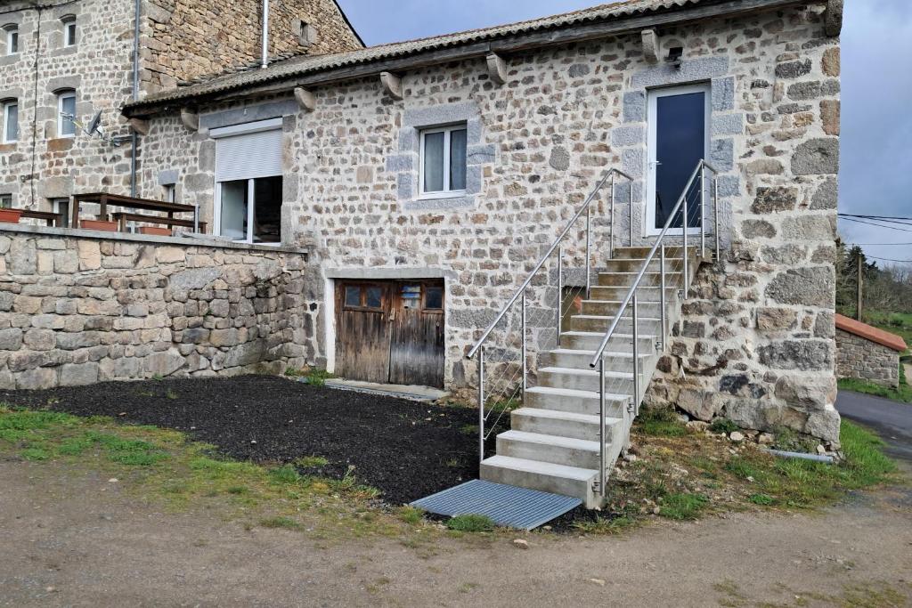 a stone building with stairs leading to a door at Gite de la margeride in Thoras
