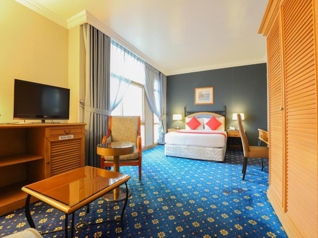 um quarto de hotel com uma cama e uma televisão em City Plaza Hotel em Fujairah