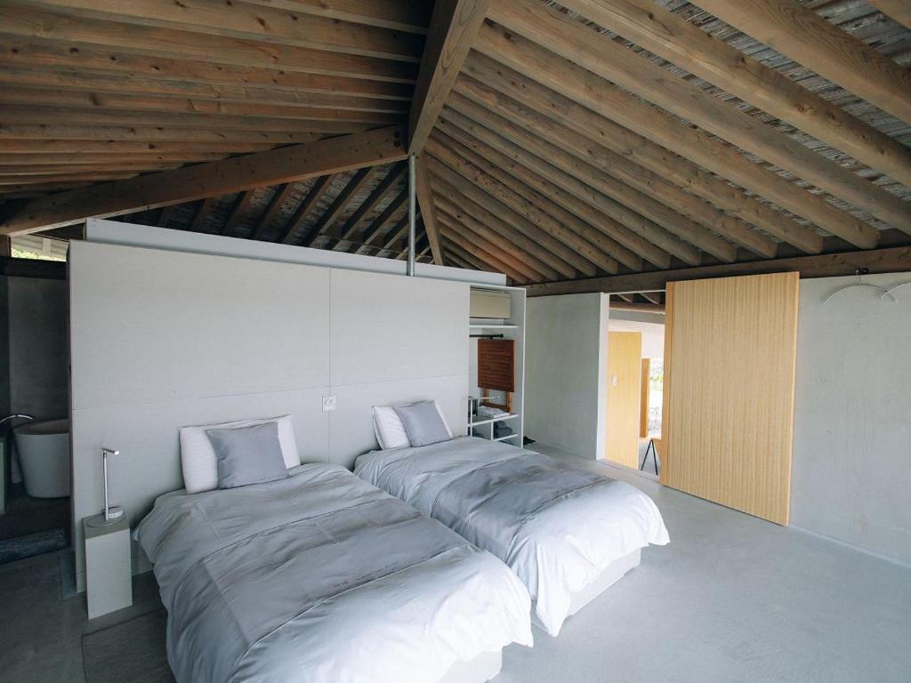 two beds in a room with wooden ceilings at Denpaku The Beachfront MIJORA in Amami