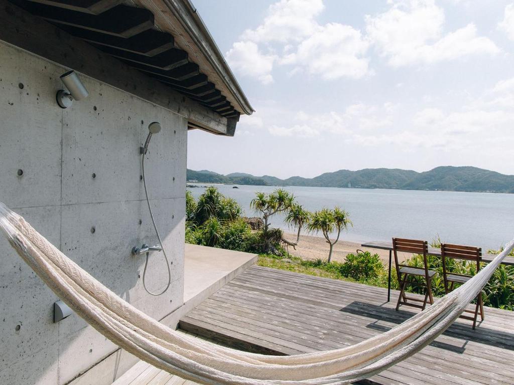 a hammock on a house with a view of the water at Denpaku The Beachfront MIJORA in Amami
