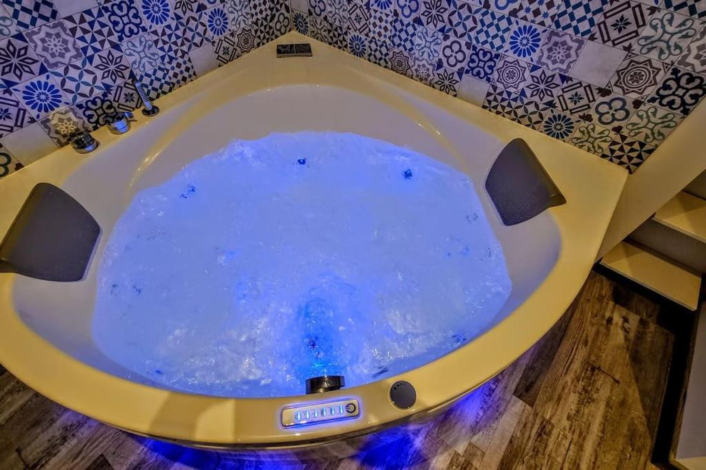 een badkamer met een bad gevuld met blauw water bij Le St Gildard in Nevers