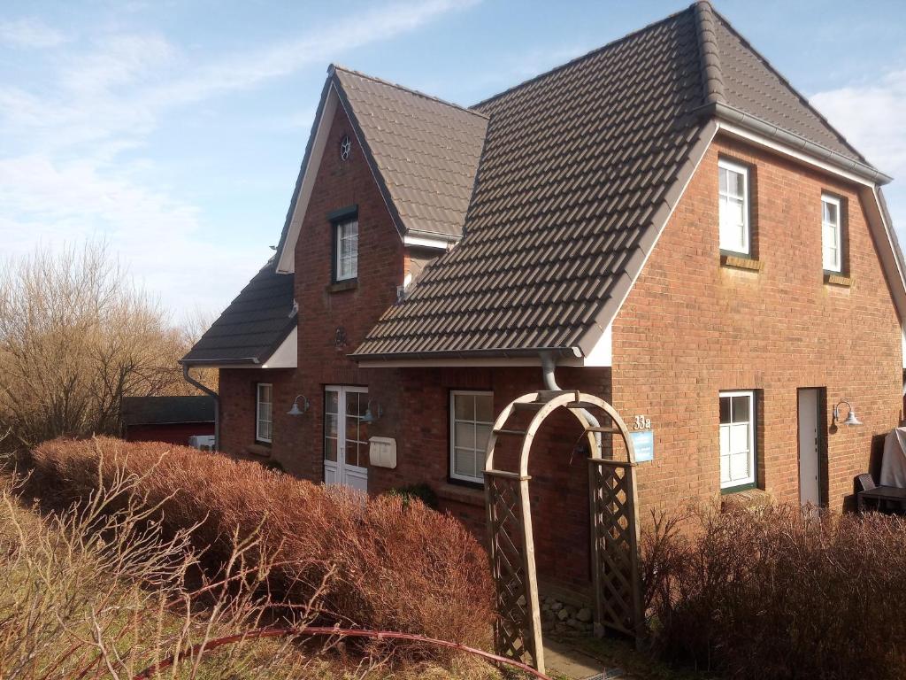 a brown brick house with a black roof at Haus Wattenblick OG in Morsum
