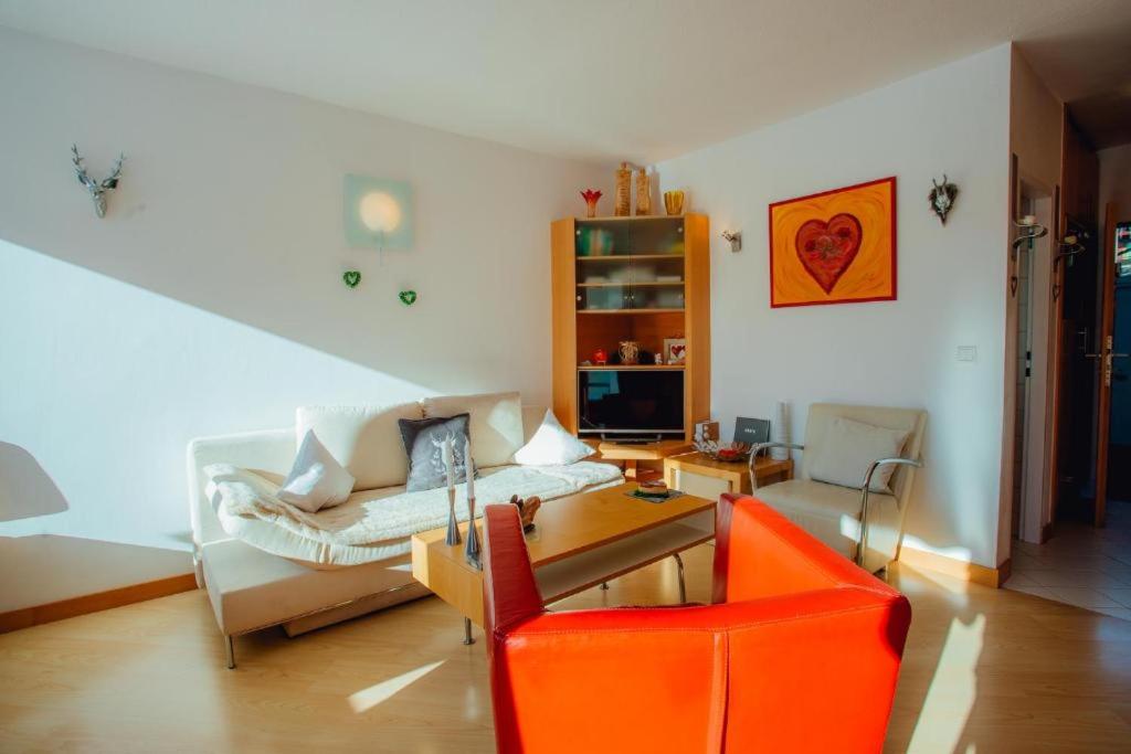 a living room with an orange chair and a couch at Appartement HERZLICHKEIT by Moni-Care in Seefeld in Tirol