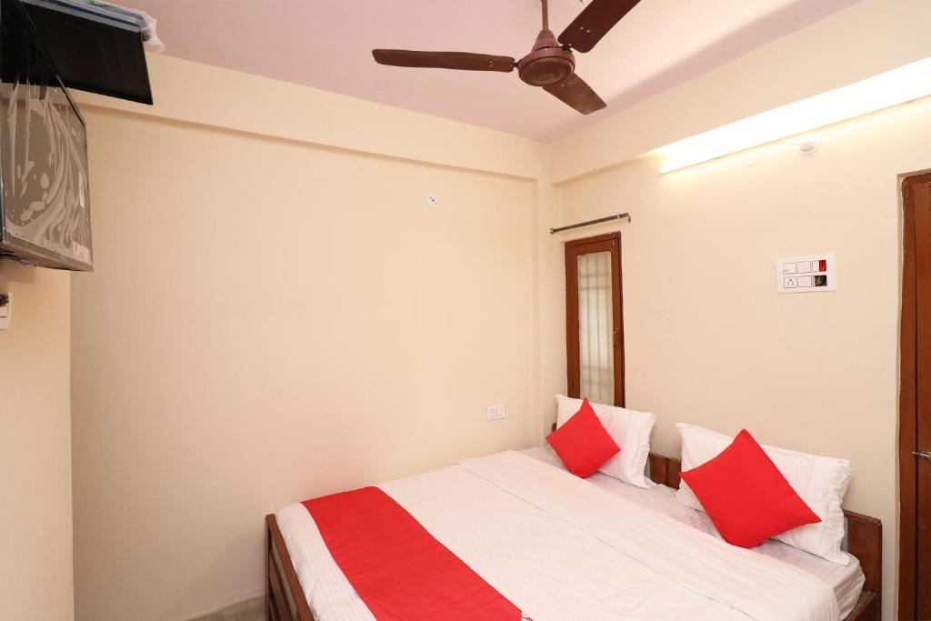 1 dormitorio con 1 cama con almohadas rojas y ventilador de techo en Flagship Hotel Midtown, en Bhopal