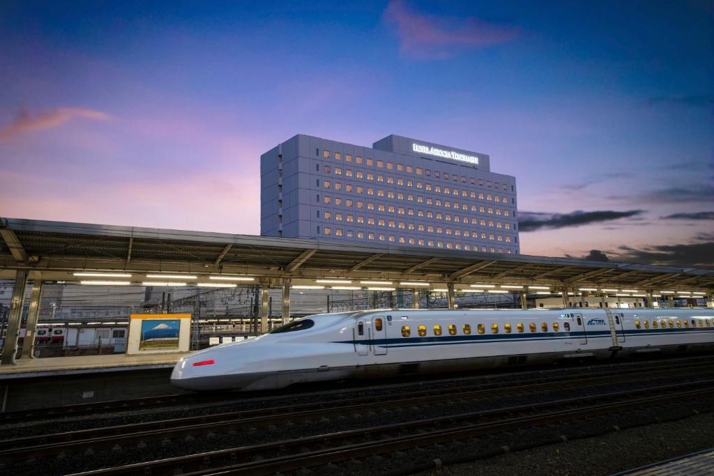 a white bullet train pulling into a train station at Hotel Associa Toyohashi in Toyohashi