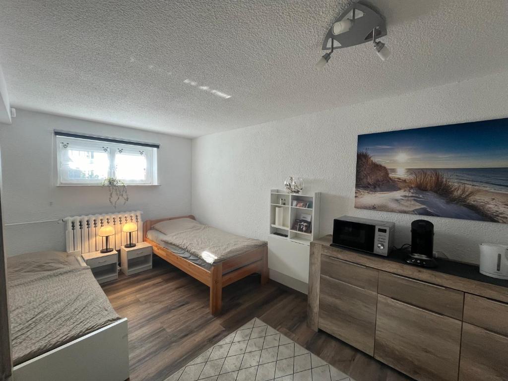 1 dormitorio con 2 camas y TV en la pared en 1-Raum Ferienwohnung Souterrain Niederorschel en Niederorschel