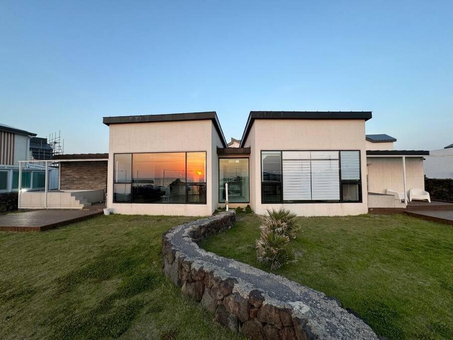 a house with a stone retaining wall in the yard at Sunyeonchae in Jeju
