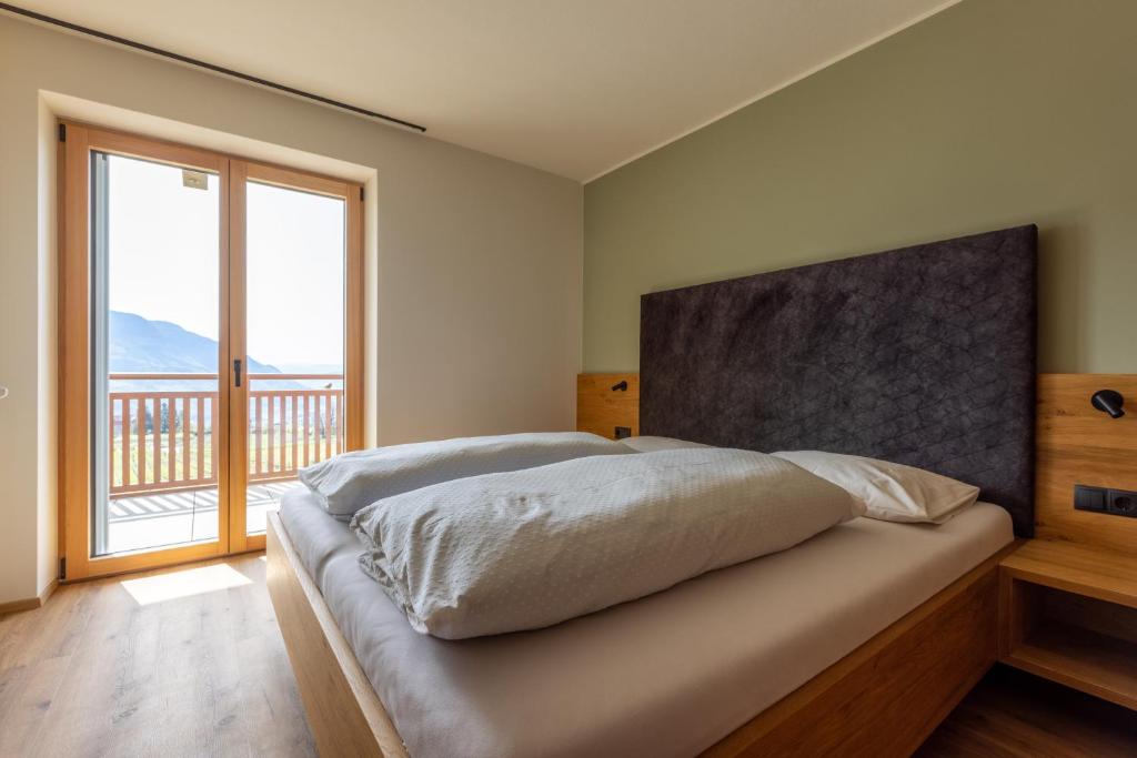 a bedroom with a large bed with a large window at Platterhof in Tirolo